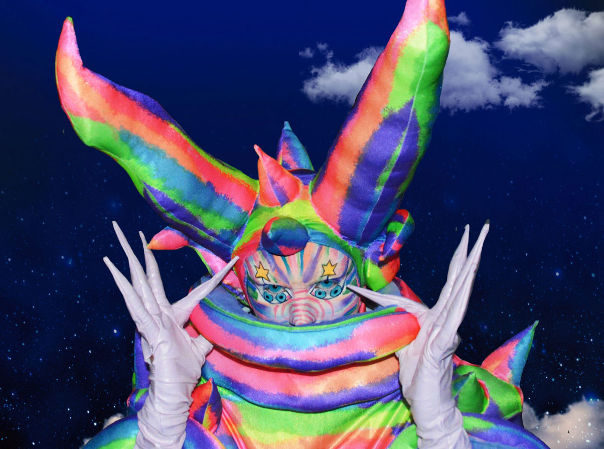 A drag queen dressed in a rainbow lizard costume