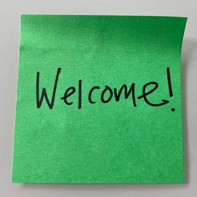 A bright green sticky note with "Welcome!" written in black marker.