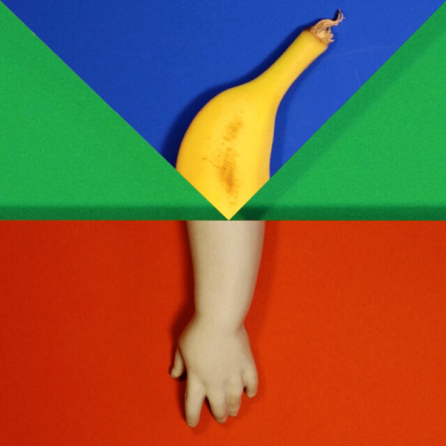 An image split in two by geometric shapes. In the top half, the top of a banana appears in a blue triangle shape. In the bottom half, the arm of a plastic doll appears in a red square shape. There is a green background behind the shapes.