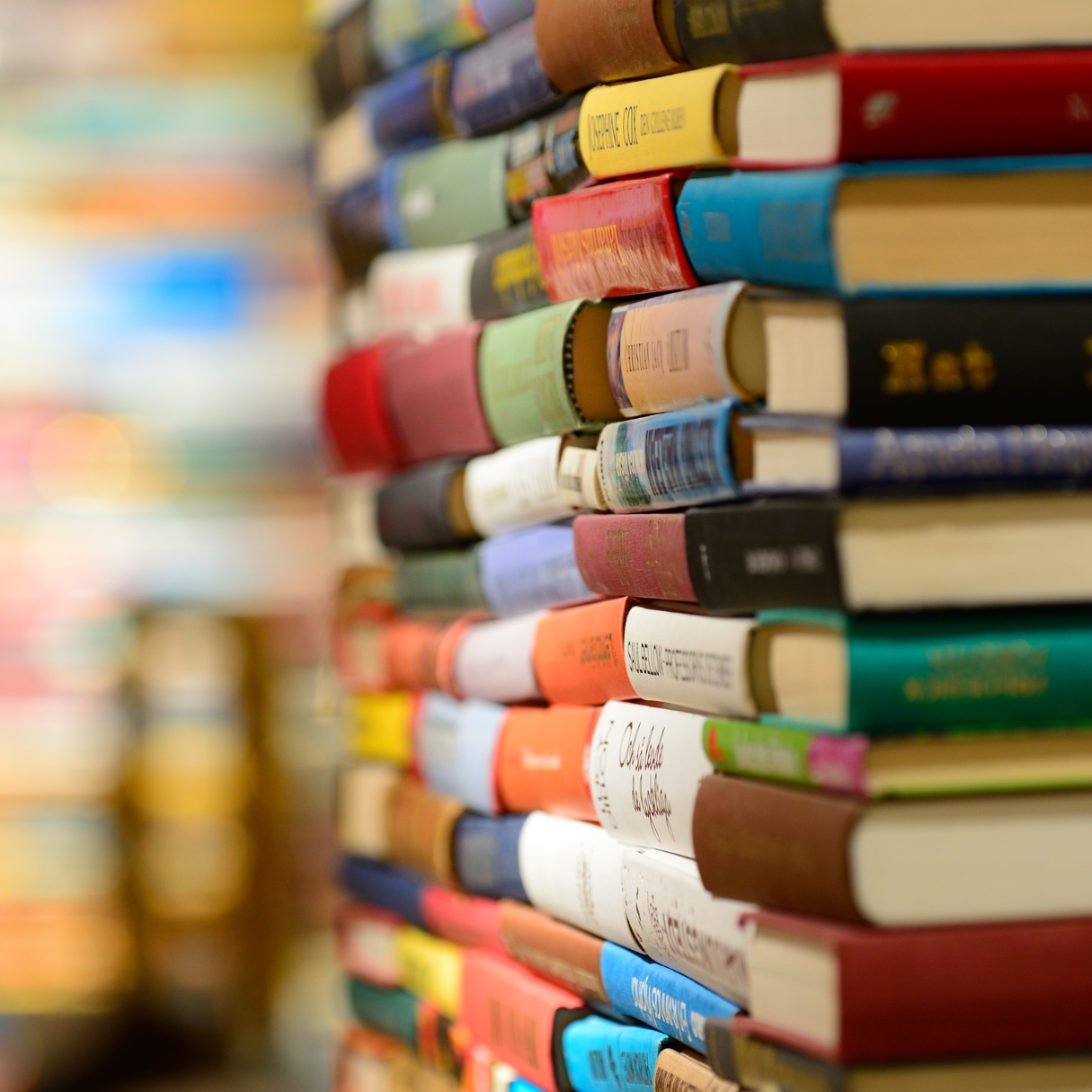 A side profile of a large stack of colourful hardcover books.