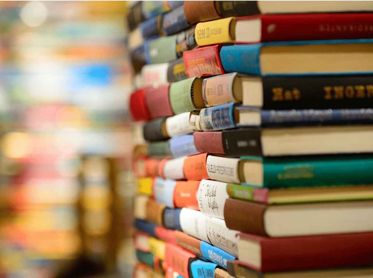 A side profile of a large stack of colourful hardcover books.